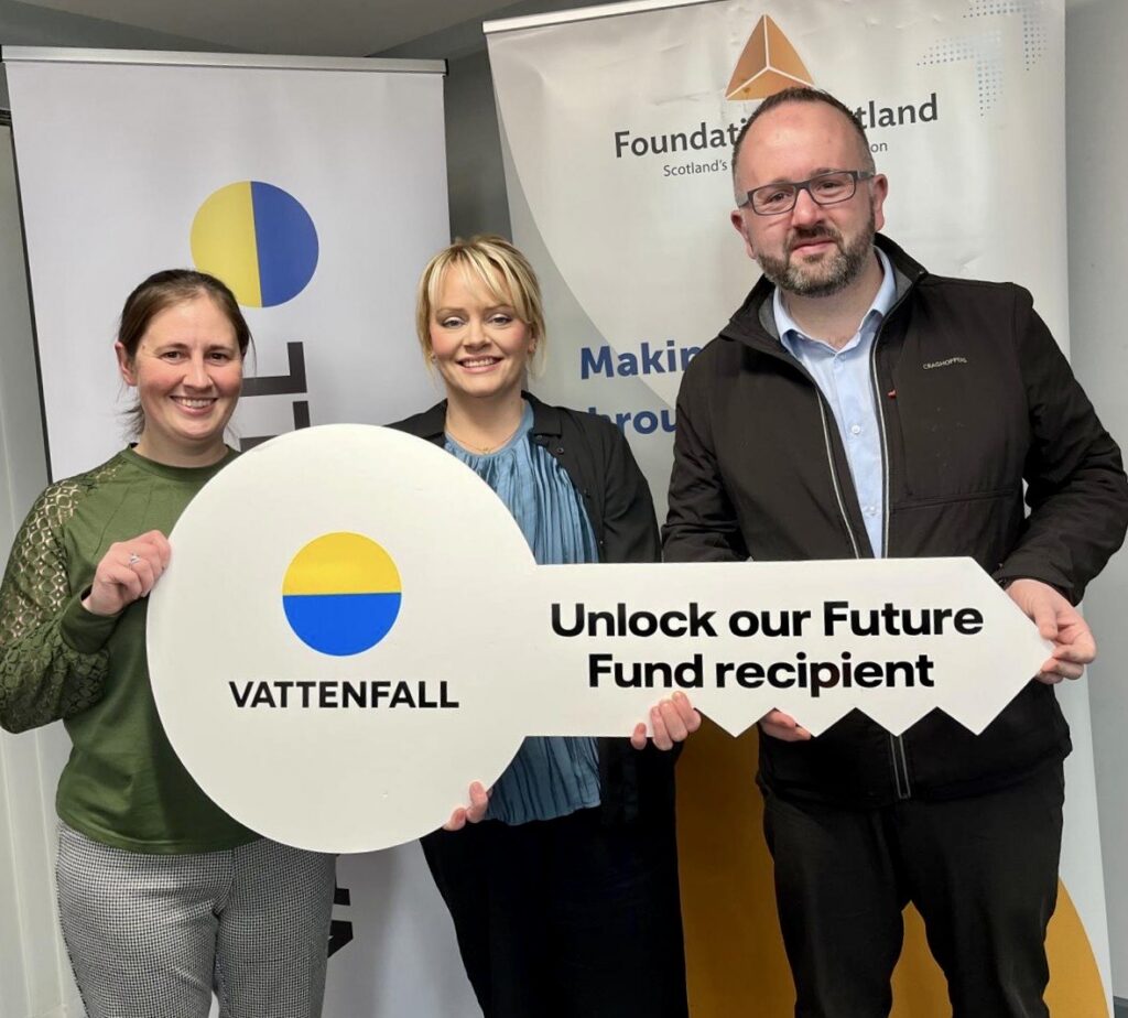 Representatives from Culter Theatre Club and Vattenfall standing with a large key labelled "Unlock our Future Fund recipient"